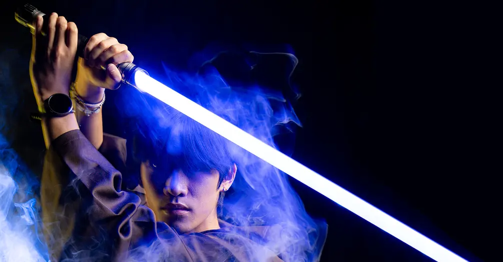 Owen Chun poses with Jedi garb and a blue lightsaber
