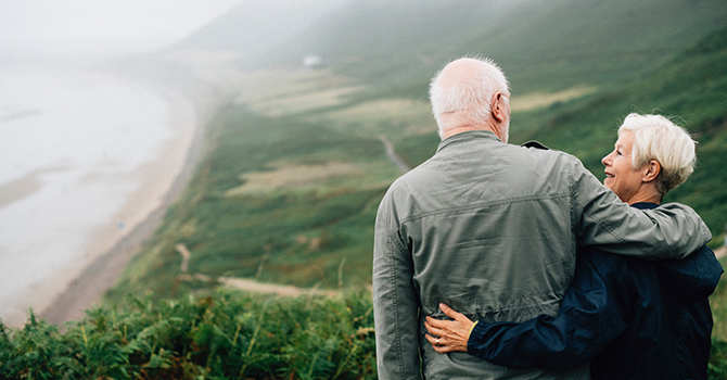 Older couple hiking, smiling and talking while looking over the countryside 
