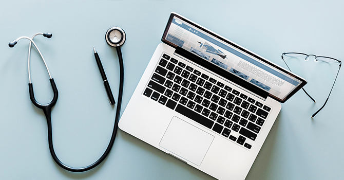 stethoscope, laptop, and glasses sitting on a desk