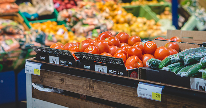 tomatoes and cucumbers sitting on a shelf inside a grocery store