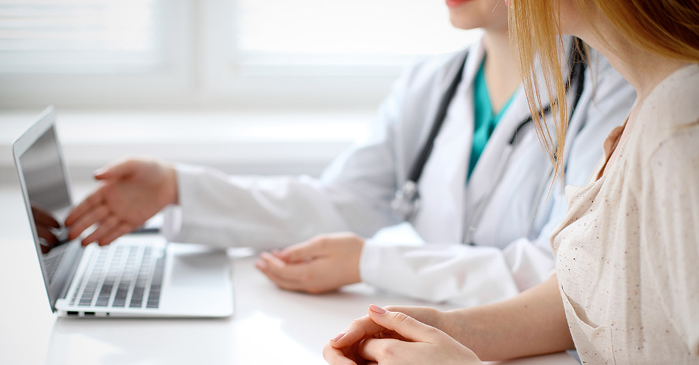 A doctor points to a computer screen with a patient.