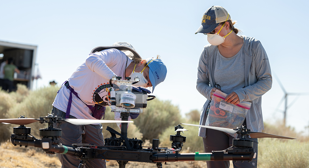 Jennifer Head, left, and student researcher Sarah Dobson load an air filter on a drone in order to sample air for Coccidioides. (Photo credit: Yuan Zhu)