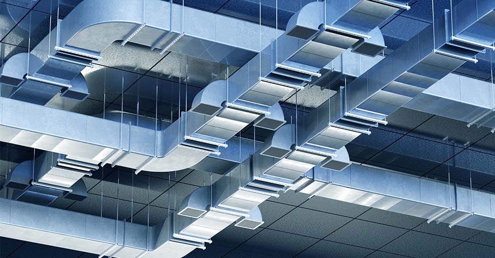 Modern commercial HVAC ductwork system with metal air ducts and ventilation components in industrial building