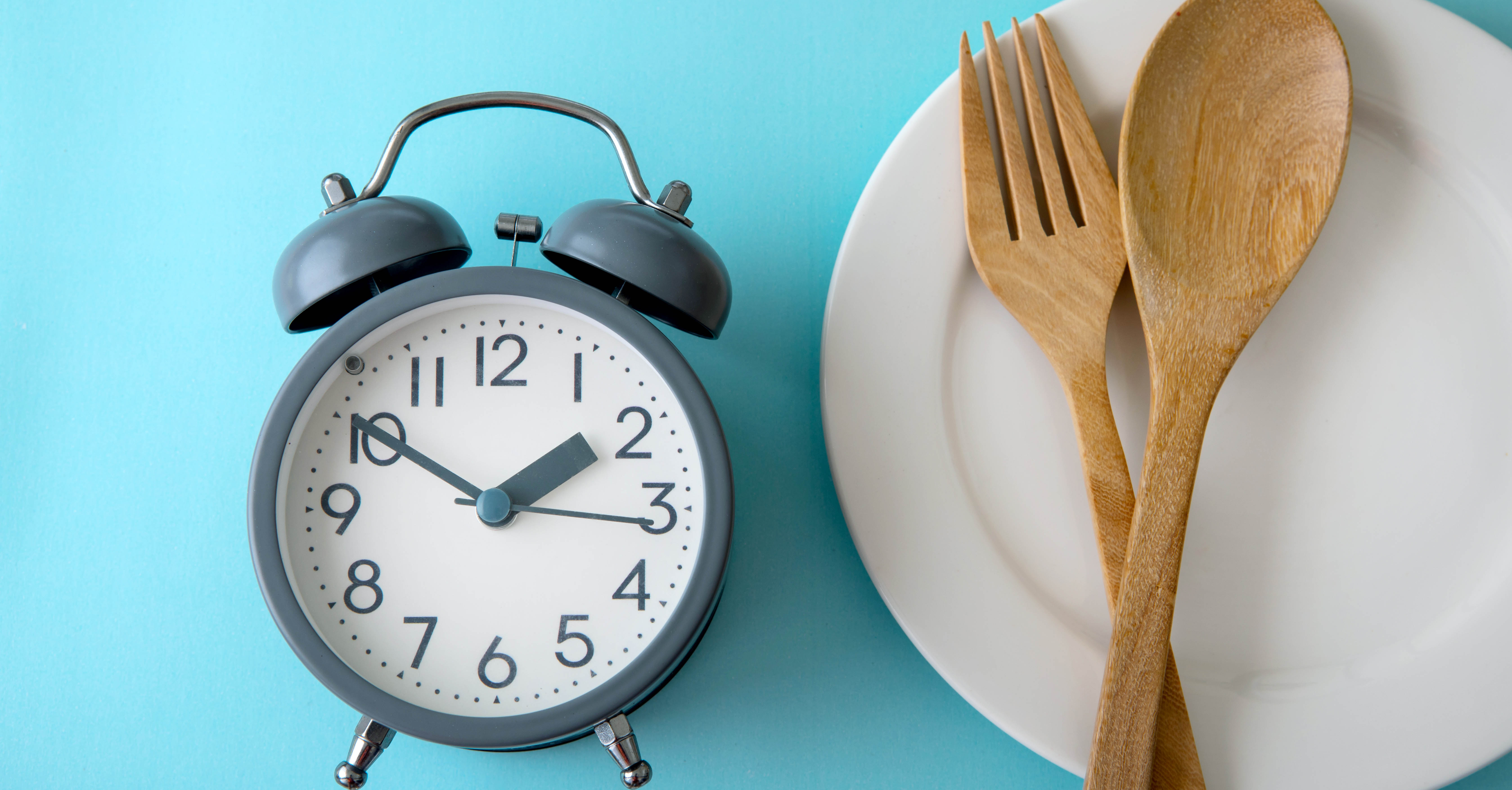 Alarm clock with a plate and wooden kitchen utensils. 