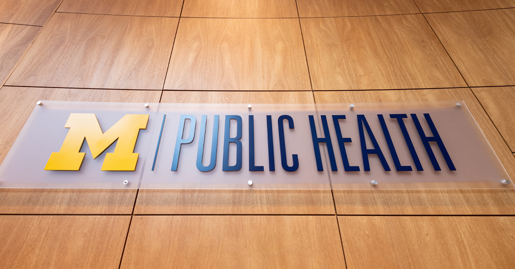 A wood-paneled wall with a sign that shows the logo for Michigan Public Health